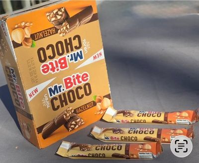 trois tablettes de chocolat posées sur une table, à côté d'une boîte de noix
