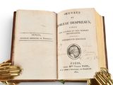 an open book with a gold glove on top of it