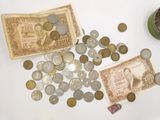 a pile of coins sitting on top of a table next to a jar of coins