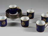 six tasses et une soucoupe ornées d'une bordure dorée, ainsi qu'une assiette sur laquelle est posé un bol
