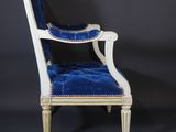 a white chair with blue velvet upholstered on a black background