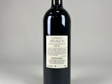 the bottle of red wine is sitting on a white surface