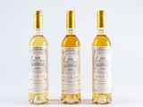 three bottles of white wine sitting next to each other on a white surface