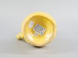 a small yellow vase with a tag on it