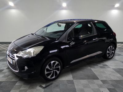 Une voiture noire est garée dans une grande pièce au sol carrelé.