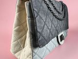 grey and white quilted handbag with chain strap on pink background
