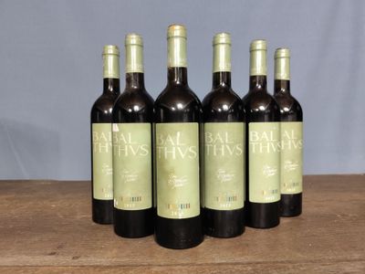 six bottles of wine are lined up on a wooden table