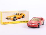 une petite voiture rouge posée à côté d'une boîte de Dinky Toys