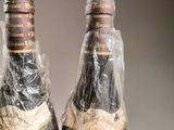 two bottles of wine wrapped in plastic wrap on a table