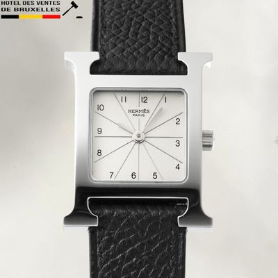 a silver square watch with a black leather strap