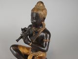 bronze statue of a boy playing a flute on a rock