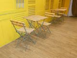 several chairs and tables in a room with yellow walls and wooden floors