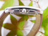 a close up of a watch on a table with leaves