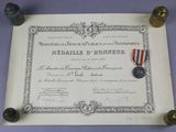 un vieux document sur lequel repose une médaille, et une autre médaille posée dessus