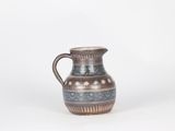 a small blue and brown pitcher sitting on a white surface