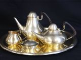 a silver tea set on a silver tray on a black background