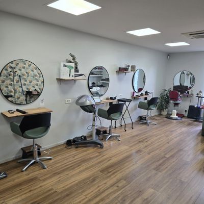 une photo d'un salon avec des fauteuils et des miroirs accrochés au mur
