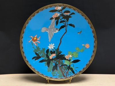 une assiette bleue ornée d'un oiseau et de fleurs