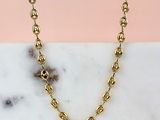 a close up of a gold chain necklace on a marble surface