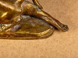 a bronze statue of a dog laying down on a pillow