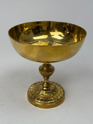 brass footed bowl on pedestal on white surface with white background