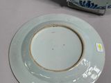 a white plate with a blue and white design on it next to a plate with a gold rim