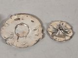 three pieces of silver metal are sitting on a white surface