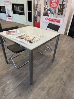 a white table with a magazine on it and a black chair in front of it