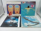 Trois albums vinyles sont posés sur une table, à côté d'une vitrine en verre
