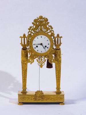 une horloge en or posée sur un socle et munie d'une cloche