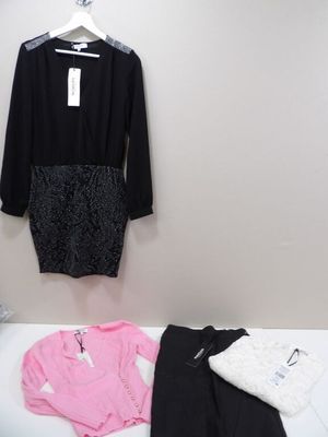 a bed with clothes on it and a coat hanging on the wall