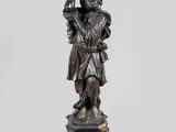 une statue en bronze d'une femme tenant un oiseau sur un piédestal
