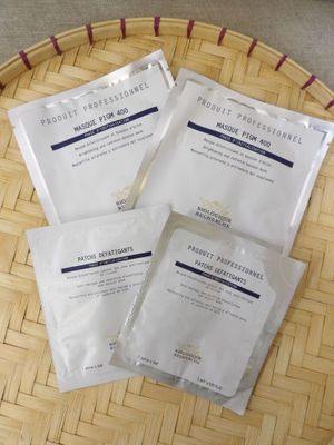 trois paquets de masques pour le visage posés sur un plateau en bambou