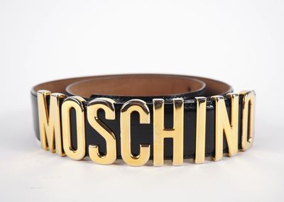 une ceinture noire et dorée sur laquelle est inscrit le mot « Moschino »