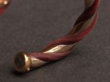 a close up of a gold and red bracelet on a black surface