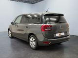 the back of a grey car in a room with a black floor