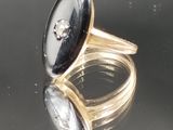 paire de bagues en or ornées de pierres noires et blanches sur une surface réfléchissante