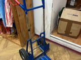 un diable bleu posé par terre à côté d'un carton