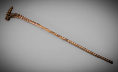 an old wooden walking stick with a wooden handle on a gray background