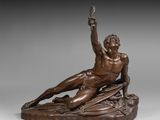 une statue en bronze représentant un homme assis sur un rocher