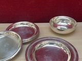 quatre assiettes en argent posées sur une table en bois, avec un mur rouge en arrière-plan