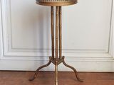 une table d'appoint ancienne en laiton avec un plateau en verre, posée sur un parquet