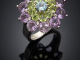 a close up of a purple and green flower ring on a black surface