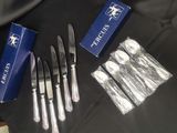 quatre fourchettes, un couteau et une boîte de couverts posés sur une table