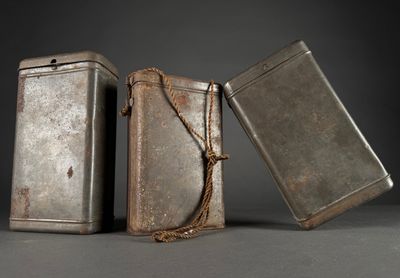 two old metal tins with a rope around them on a gray surface