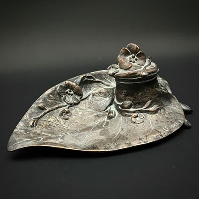 une assiette en argent ornée d'une fleur sur un fond noir