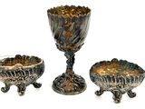 three silver vases sitting next to each other on a white surface