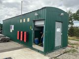 un bâtiment écologique dont la porte est ouverte et auquel est raccordé un tuyau d'arrosage