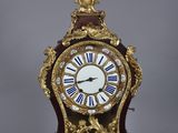 a clock that is sitting on a stand on a gray surface