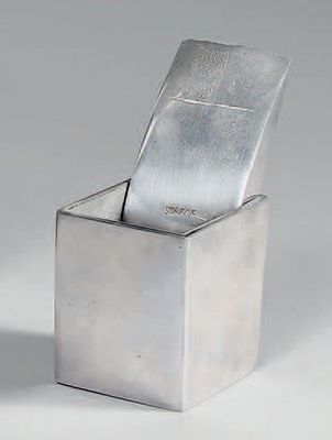 un récipient en argent muni d'un couvercle en argent, posé sur une surface blanche